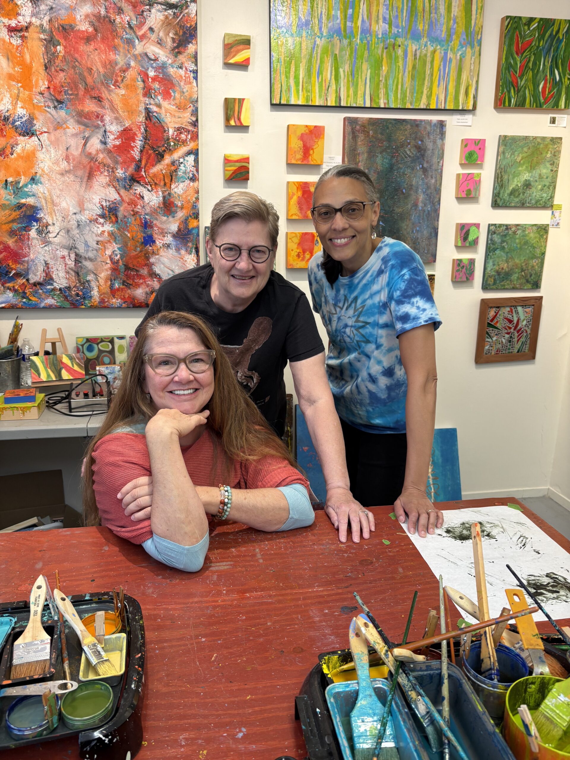 Three artists who revived the Davis Art Studio Tour after the pandemic stand together in one of the artist's painting studios
